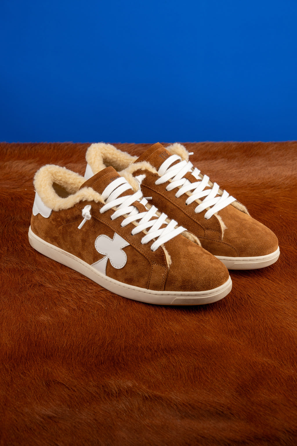 Geneva Wool Brown, pair on cowhide against a blue backdrop