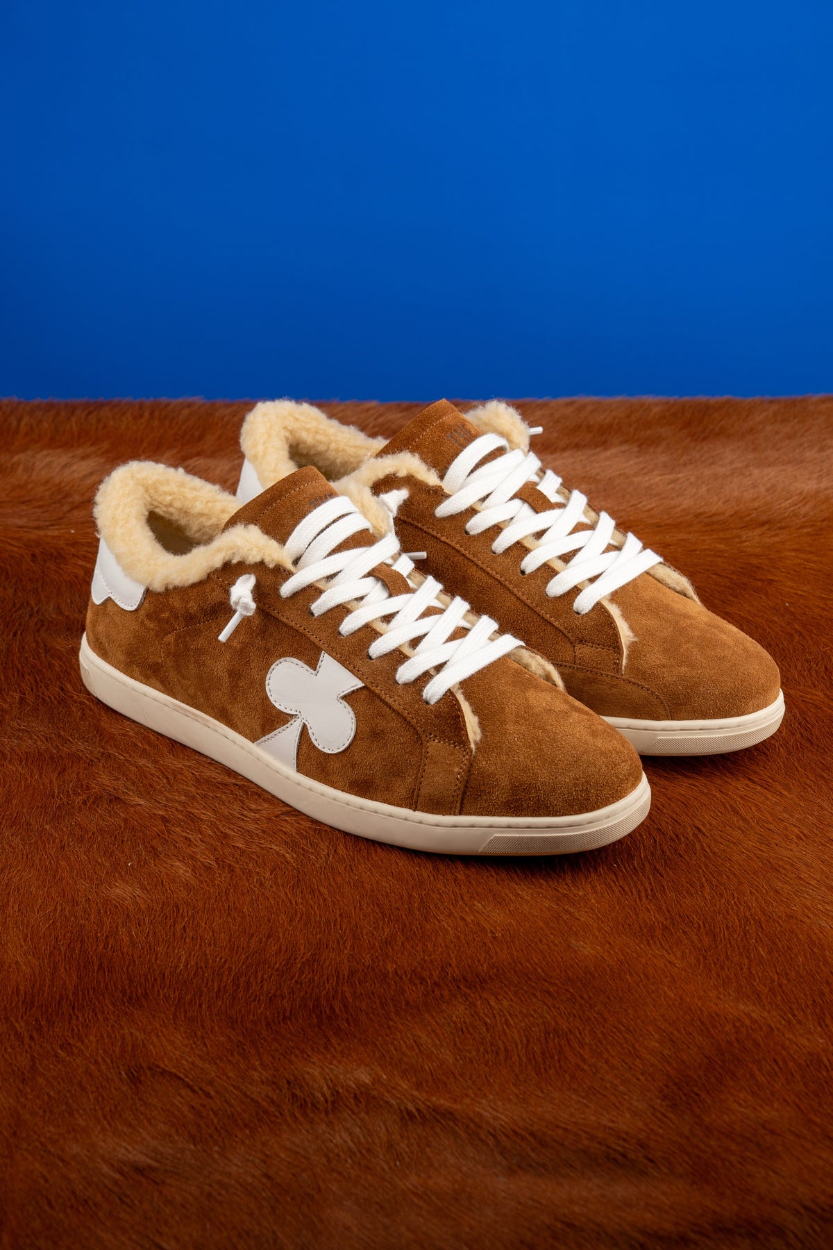 Geneva Wool Brown, pair on cowhide against a blue backdrop