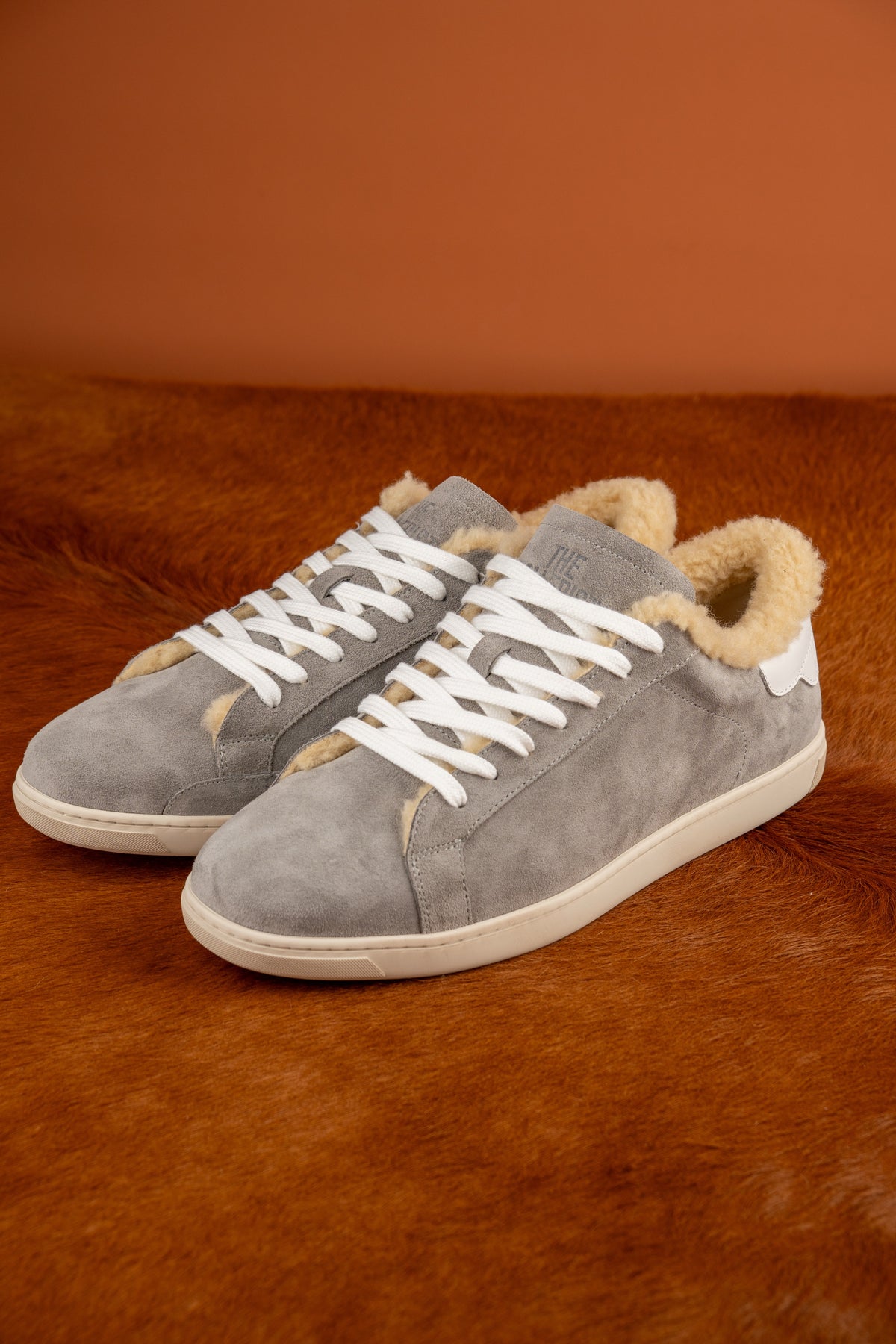 Geneva Wool Grey Suede Unsigned, pair on cowhide against an orange backdrop
