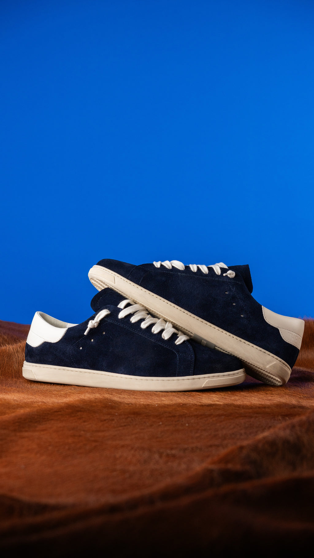 Geneva Dark Blue Unsigned, pair stacked on cowhide against a blue backdrop